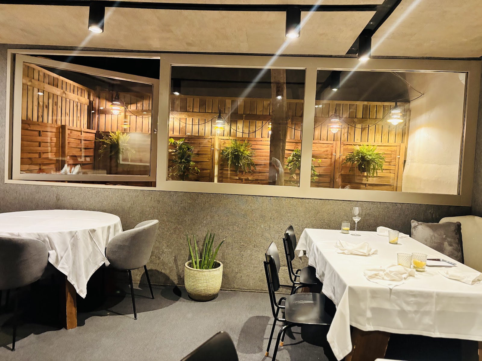 Comedor de Coure con mesas vestidas de blanco y ventanas interiores de madera